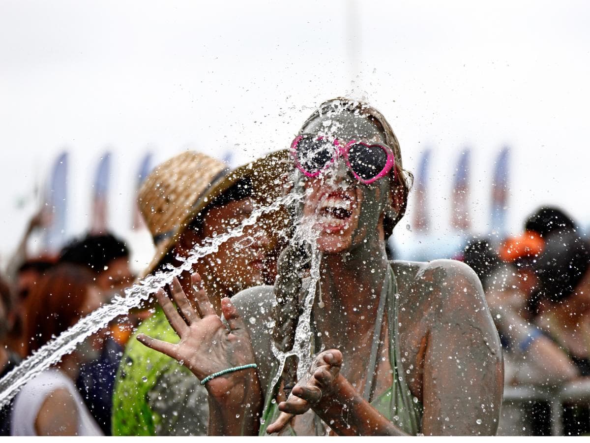 A woman washing the mud off her face under a spray of water at the Boryeong Mud Festival
