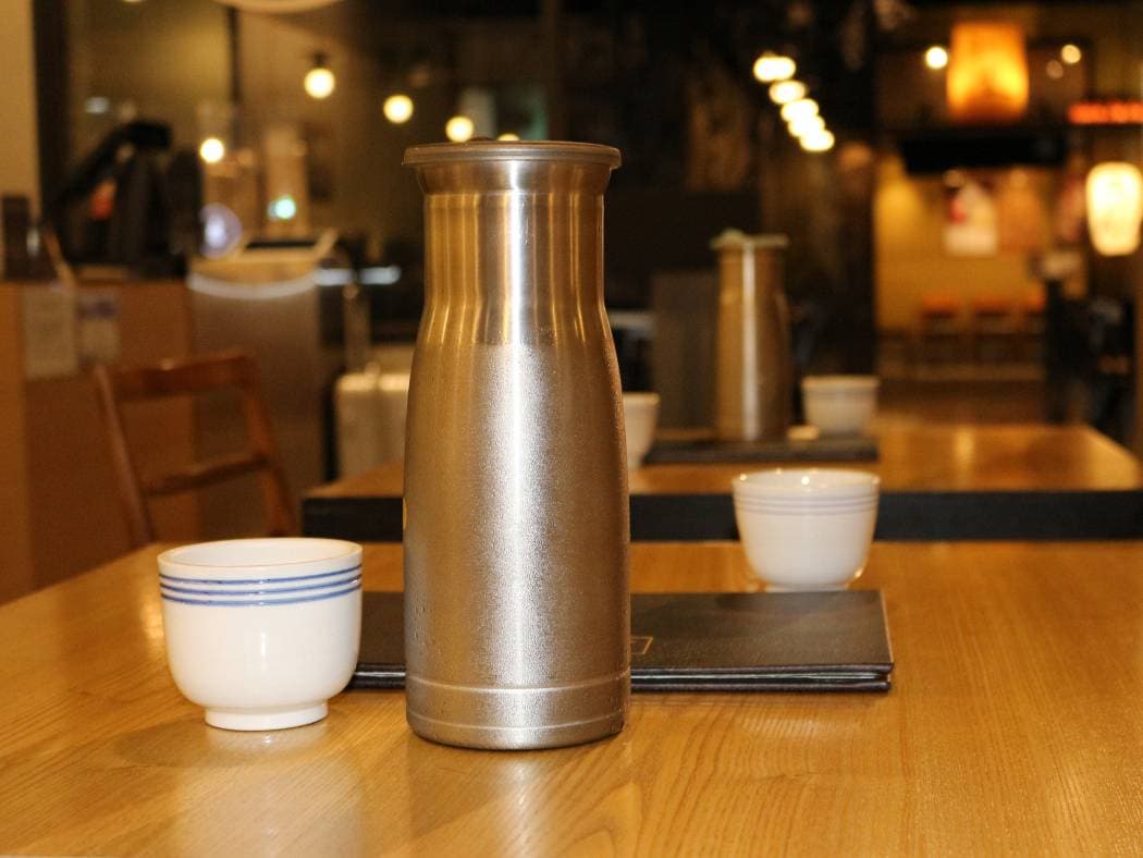 Two water cups and a water bottle are placed on the restaurant table.