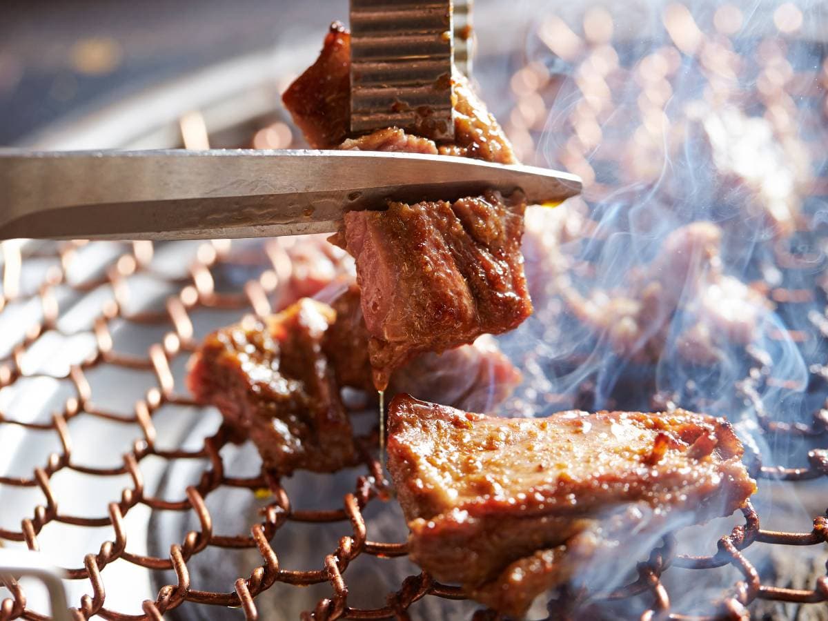 While grilling meat, cutting meat with scissors on the grill
