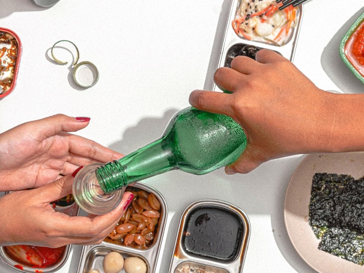 A woman holds a Korean soju glass in both hands for keeping the etiquette of receiving soju from the other person.